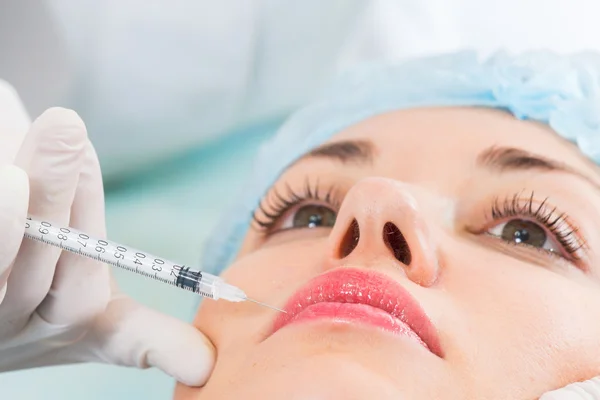 Kosmetikerin spritzt der Patientin Injektion ins Gesicht — Stockfoto
