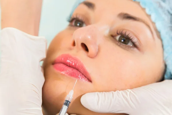 Beautician makes injection into the patient's face