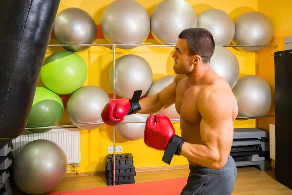 Uomo muscoloso in guanti da boxe in palestra — Foto Stock