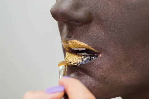 Gouden lippen op donkere make-up gezicht — Stockfoto