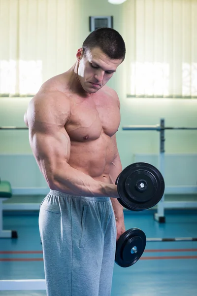 Homem musculoso trabalhando com halteres — Fotografia de Stock