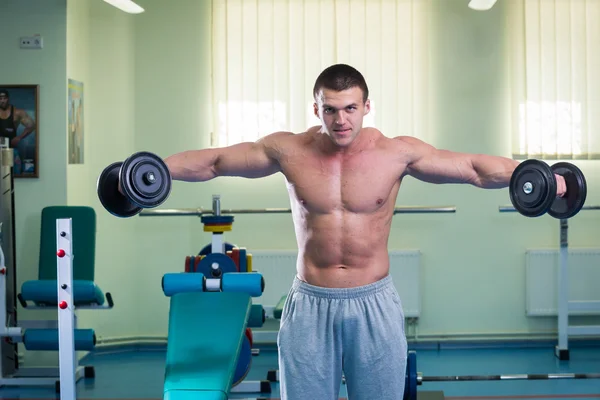 Homem musculoso trabalhando com halteres — Fotografia de Stock