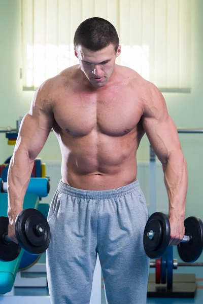 Homem musculoso trabalhando com halteres — Fotografia de Stock