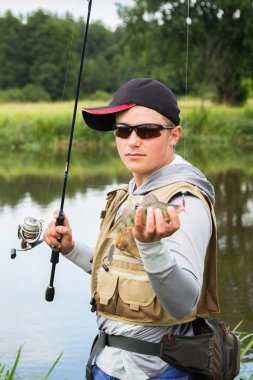 Bir levrek elinde tutan balıkçı