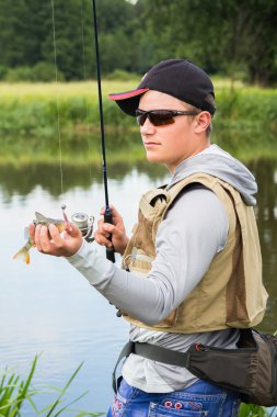 Bir levrek elinde tutan balıkçı