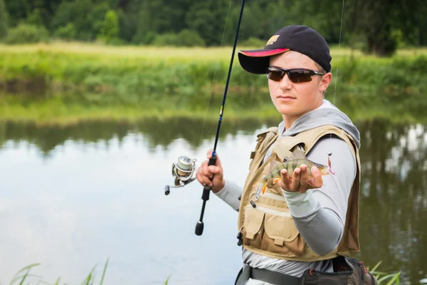 Fischer mit einem Barsch in der Hand — Stockfoto