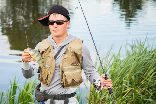 Fischer mit einem Barsch in der Hand — Stockfoto