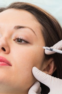 Güzellik uzmanı hastanın yüz içine enjeksiyon yapar