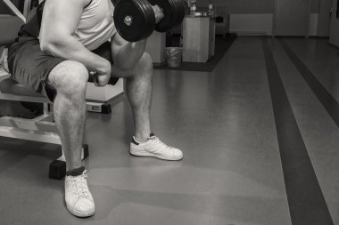 Adam bir dumbbell tutarak kaslı kollarıyla