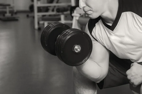 Man with muscular arms holding a dumbbell — Stock Photo, Image