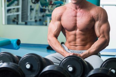 Salonda oturan çıplak gövde ile vücut geliştirmeci