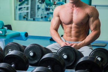 Salonda oturan çıplak gövde ile vücut geliştirmeci