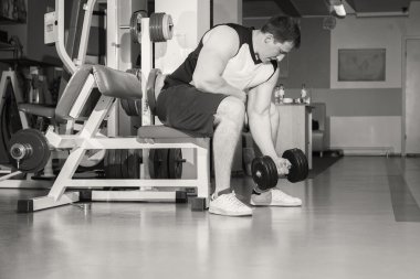 Adam bir dumbbell tutarak kaslı kollarıyla