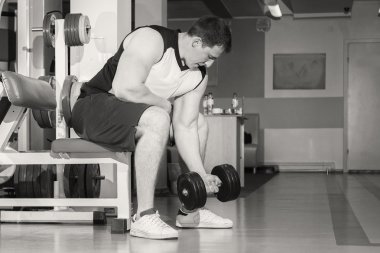 Adam bir dumbbell tutarak kaslı kollarıyla