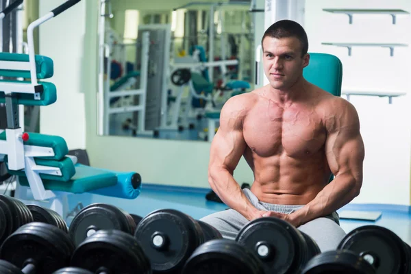 Bodybuilder with naked torso sitting in the gym — Stock Photo, Image