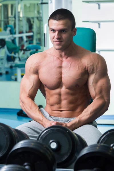 Bodybuilder avec torse nu assis dans la salle de gym — Photo