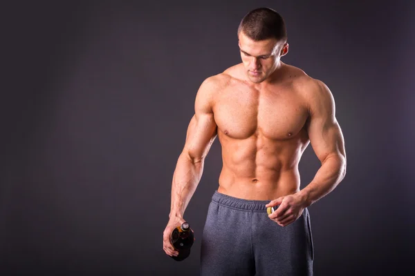 Muscular guy pouring beer on the ground — Stock Photo, Image