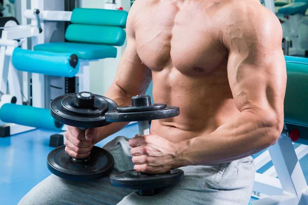 Mann macht Übungen mit Kurzhanteln im Fitnessstudio — Stockfoto