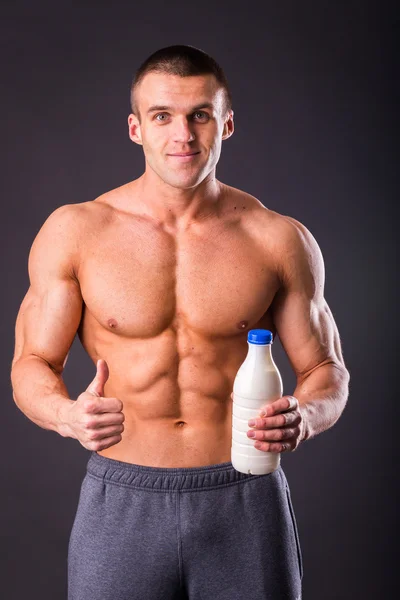 Bodybuilder håller en flaska mjölk — Stockfoto