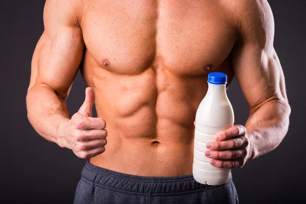 Bodybuilder holding a bottle of milk — Stock Photo, Image