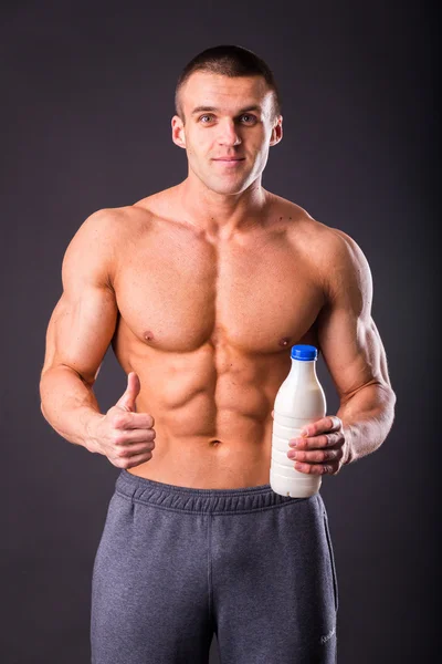 Bodybuilder holding a bottle of milk — Stock Photo, Image