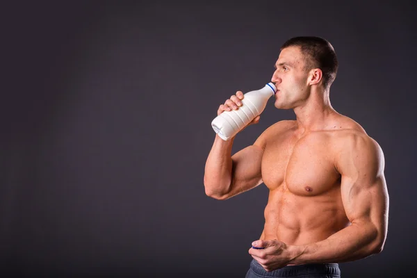 Bodybuilder holding a bottle of milk — Stock Photo, Image