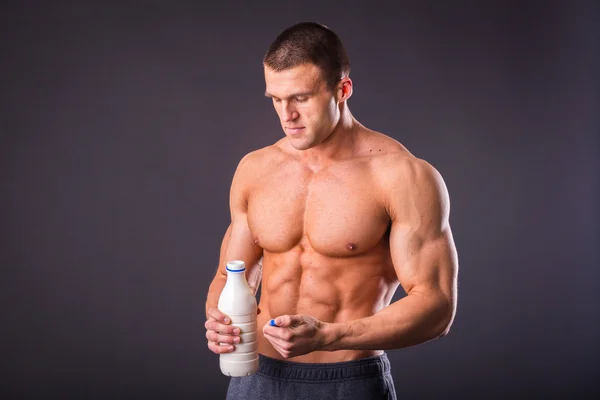 Bodybuilder holding a bottle of milk — Stock Photo, Image