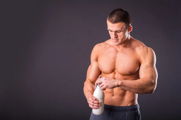 Bodybuilder håller en flaska — Stockfoto