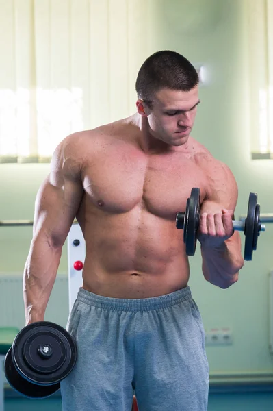 Bodybuilder makes exercises with dumbbells — Stock Photo, Image