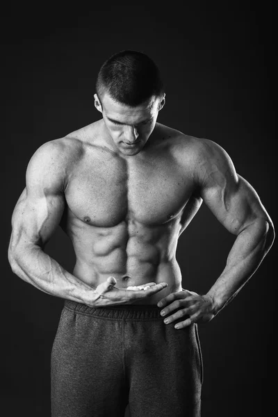 Homem atlético segurando suplementos nutricionais — Fotografia de Stock