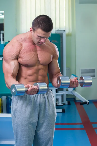 Homem musculoso trabalhando com halteres — Fotografia de Stock