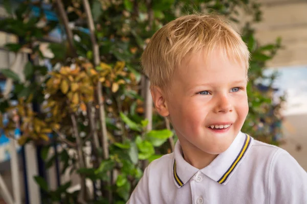 Sonriente niño sobre un fondo de plantas —  Fotos de Stock