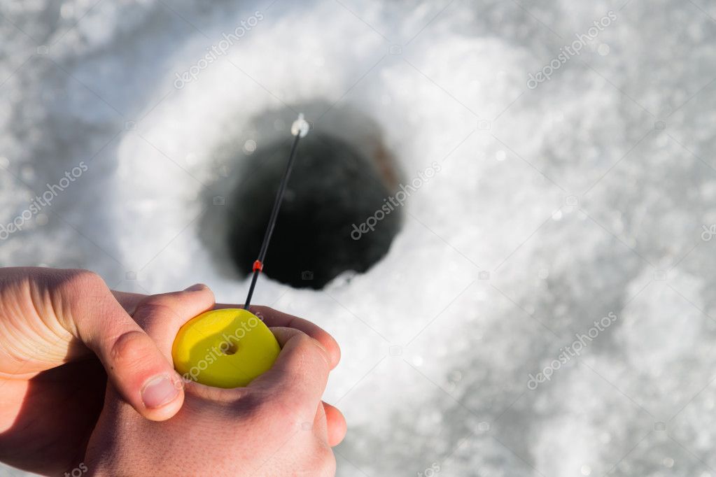 Fisherman on ice fishing from the well