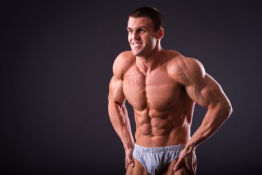 Siyah bir arka plan üzerinde poz vücut geliştirmeci