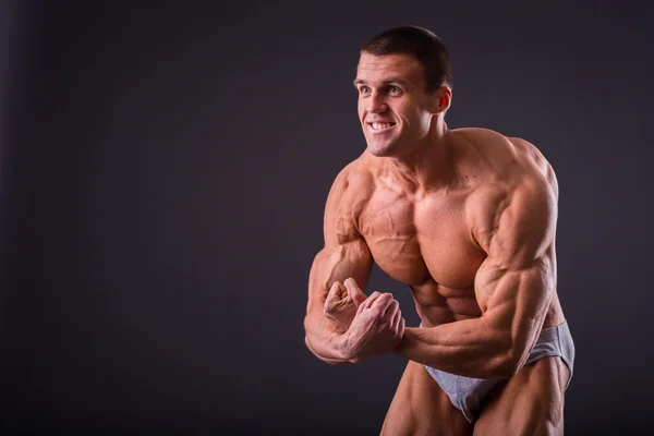 Bodybuilder posing on a black background — Stock Photo, Image