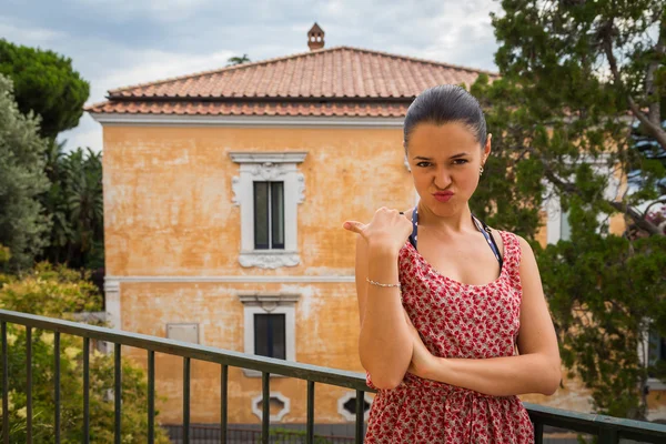 Brunette in a red dress on a balcony — Stock Photo, Image