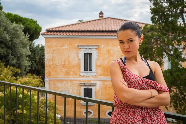 Brunette in a red dress on a balcony — Stock Photo, Image