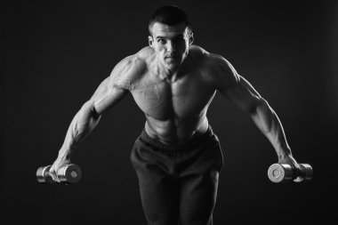 Yakışıklı kaslı adam egzersizleri dumbbells ile yapma
