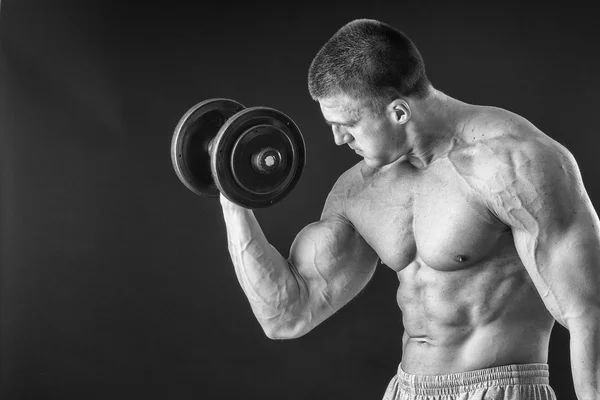 Schöner muskulöser Mann, der mit Hanteln trainiert — Stockfoto