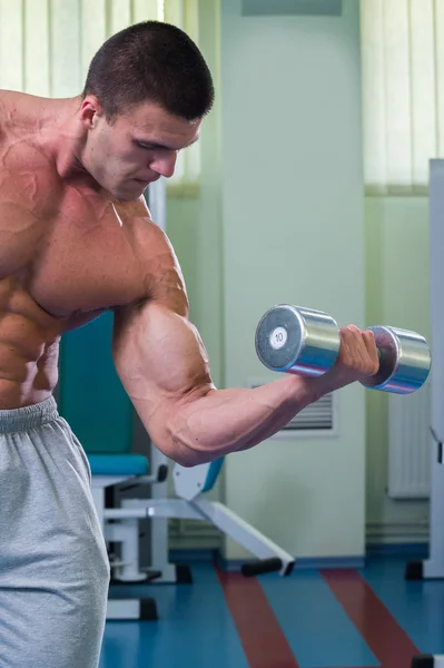 Schöner muskulöser Mann, der mit Hanteln trainiert — Stockfoto