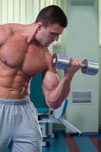 Bonito homem musculoso trabalhando com halteres — Fotografia de Stock