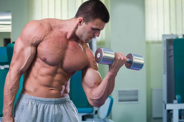 Hombre musculoso guapo haciendo ejercicio con pesas — Foto de Stock