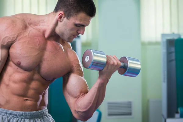 Bonito homem musculoso trabalhando com halteres — Fotografia de Stock