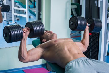 adam dumbbells ile bir spor salonu