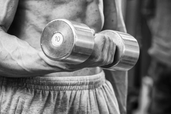 Man in een sportschool met halters — Stockfoto