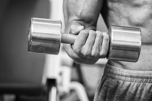 Hombre en un gimnasio con mancuernas — Foto de Stock