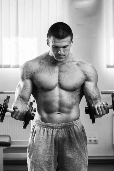 Homme dans une salle de gym avec haltères — Photo