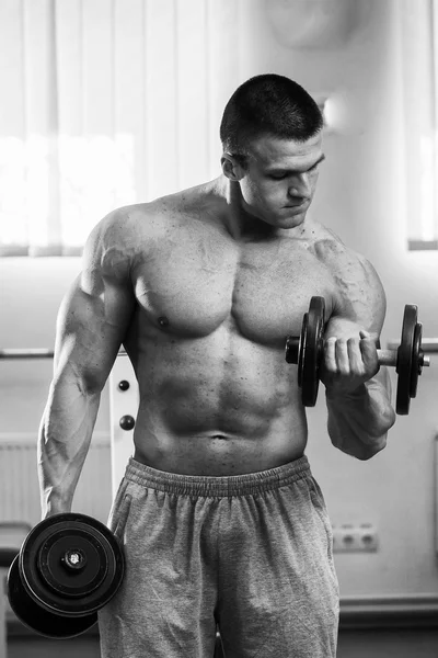 Homme dans une salle de gym avec haltères — Photo