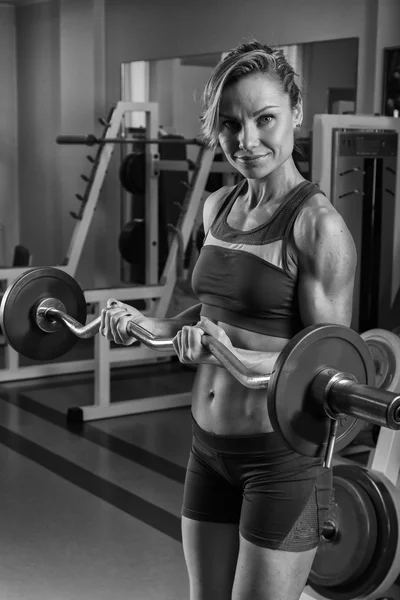 金发女郎训练肌肉发达的身体，在健身房里 — 图库照片