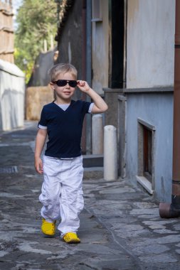 Eski şehrin sokaklarında gözlüklü küçük çocuk